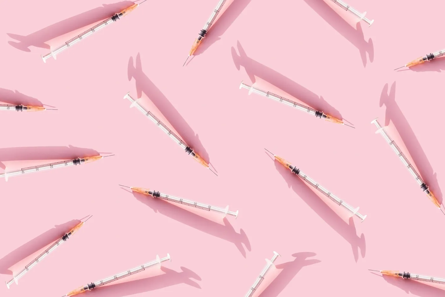 A pink background with many syringes on it.